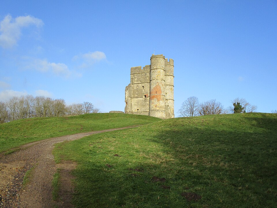 Donnington Castle gatehouse standing on a grassy hill beneath a clear blue sky.